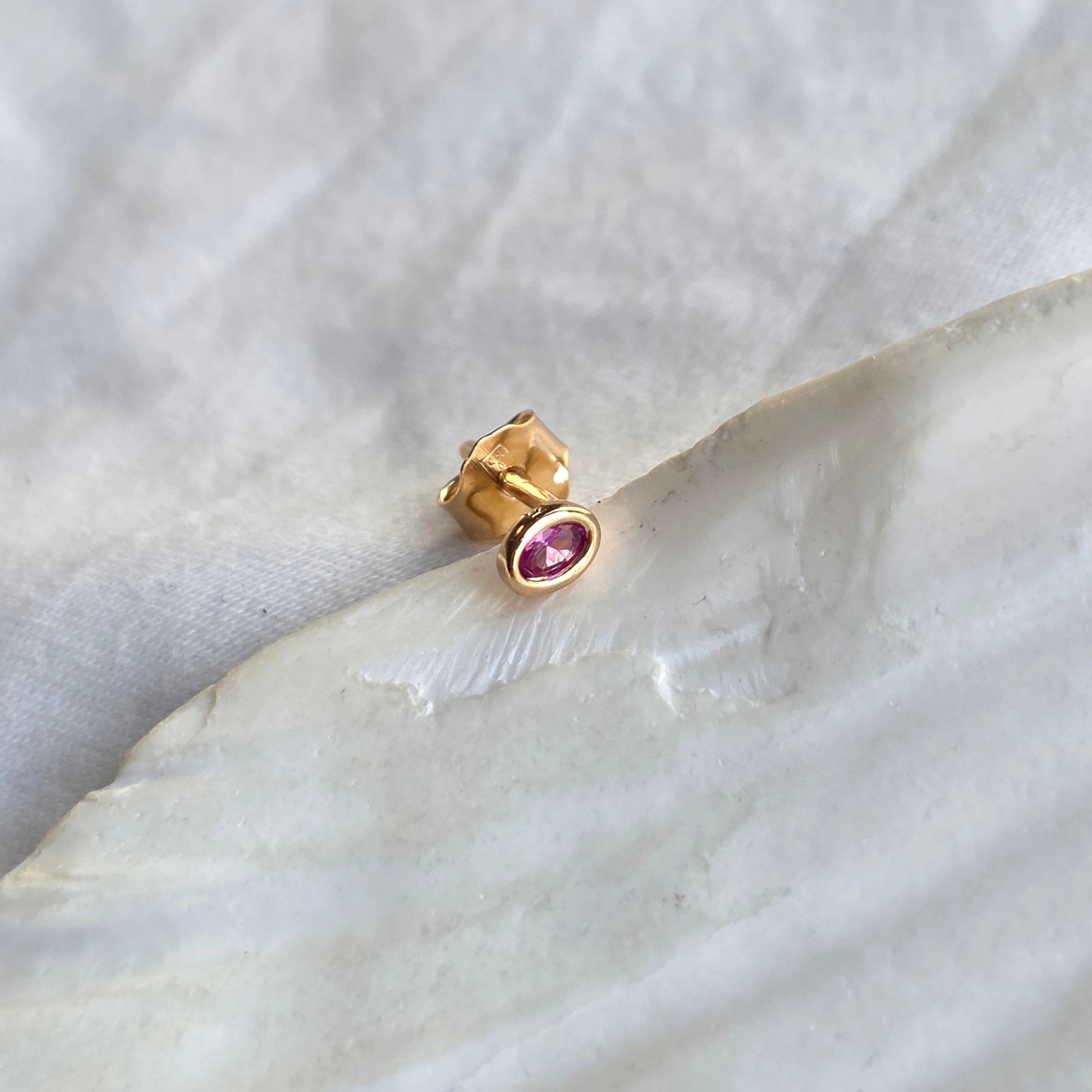 Puce d'oreille Rosa posée à plat, pierre ovale rose vif vue de face