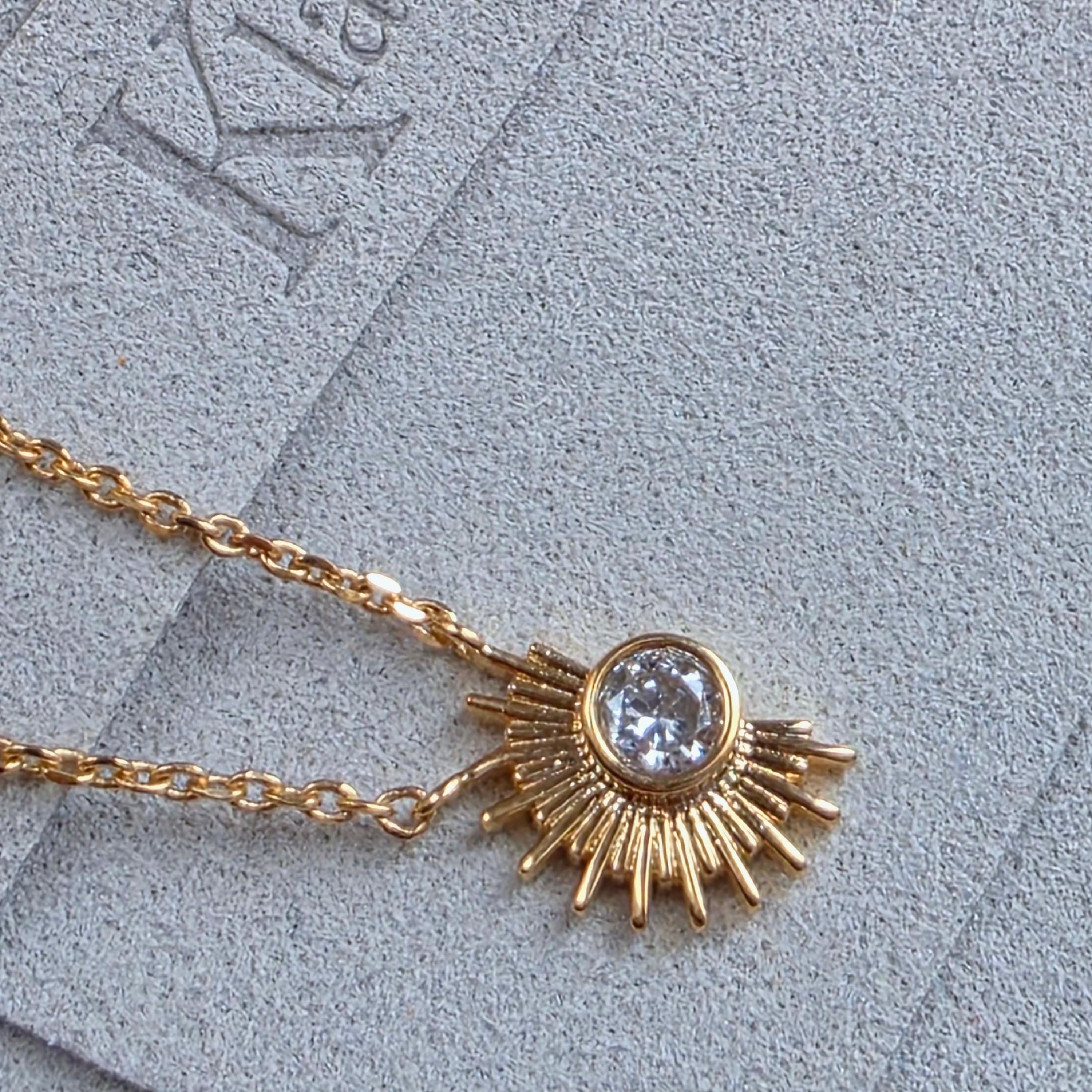 Zoom sur le bijou Orphé en plaqué or avec cristal, symbole de lumière intérieure et de renouveau.

