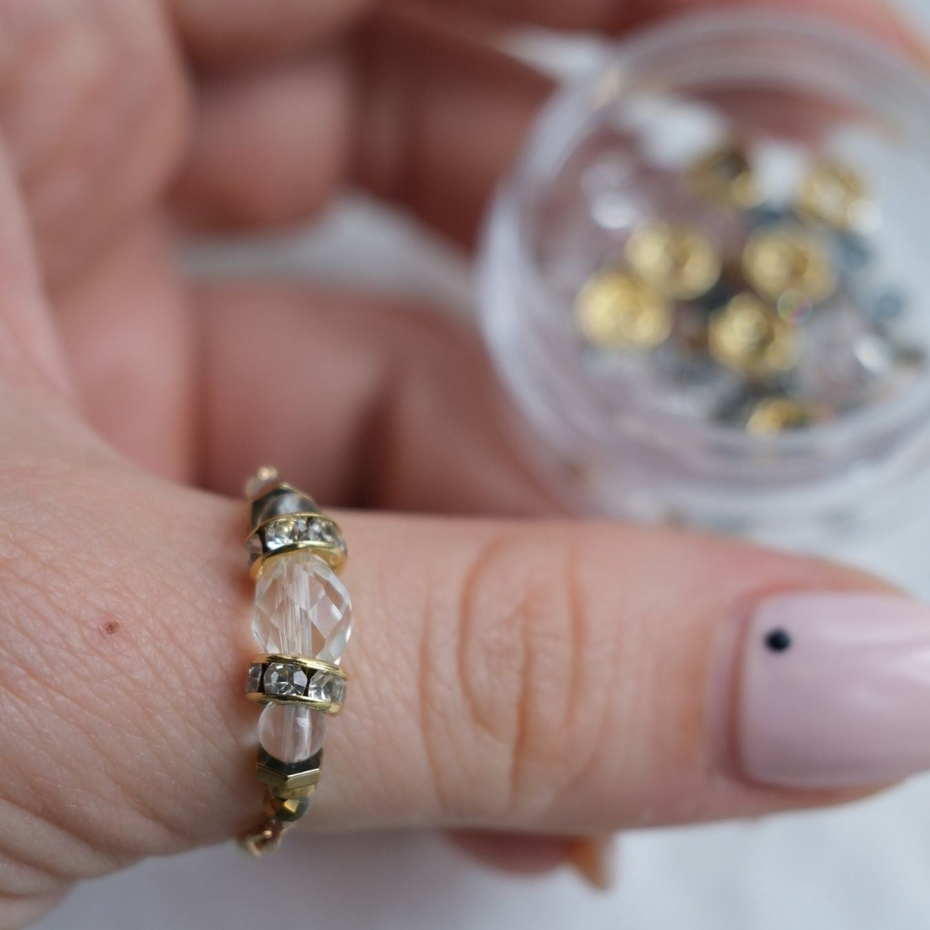 Bague artisanale en cristal de roche et hématite posée sur fond minimaliste.