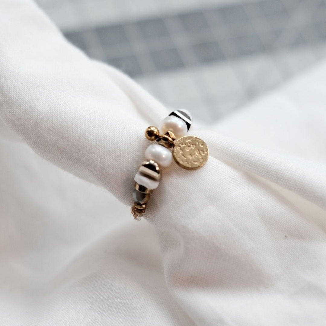 Bague contemporaine en perles de culture et hématite, montée sur élastique discret avec coquillage palourde, esprit naturel et moderne.