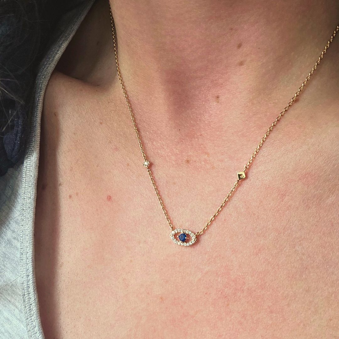 Bijou fait main en acier inoxydable doré avec symbole d’œil protecteur et éclats lumineux.