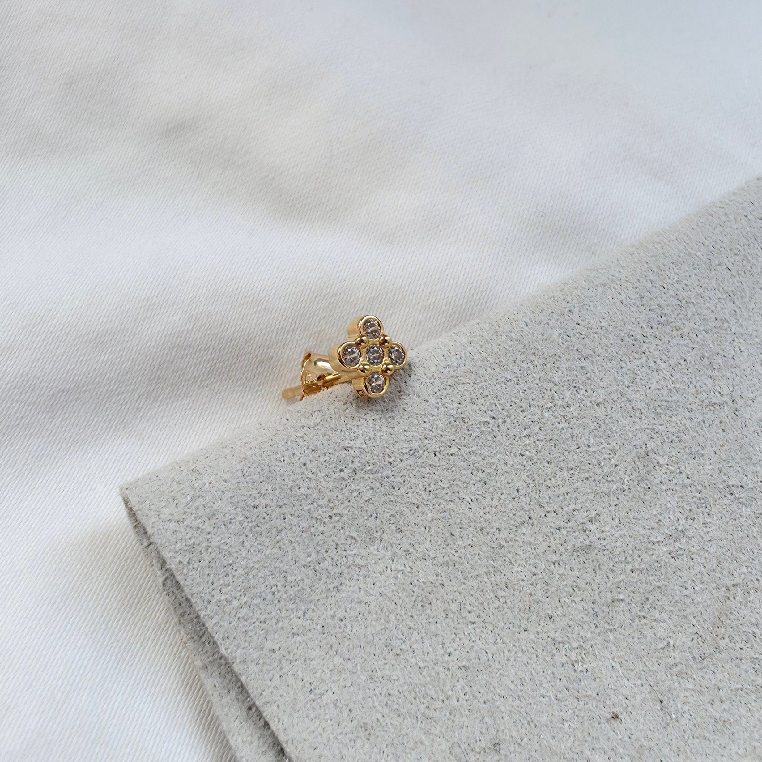 Boucle d’oreille minimaliste dorée posée sur tissu clair